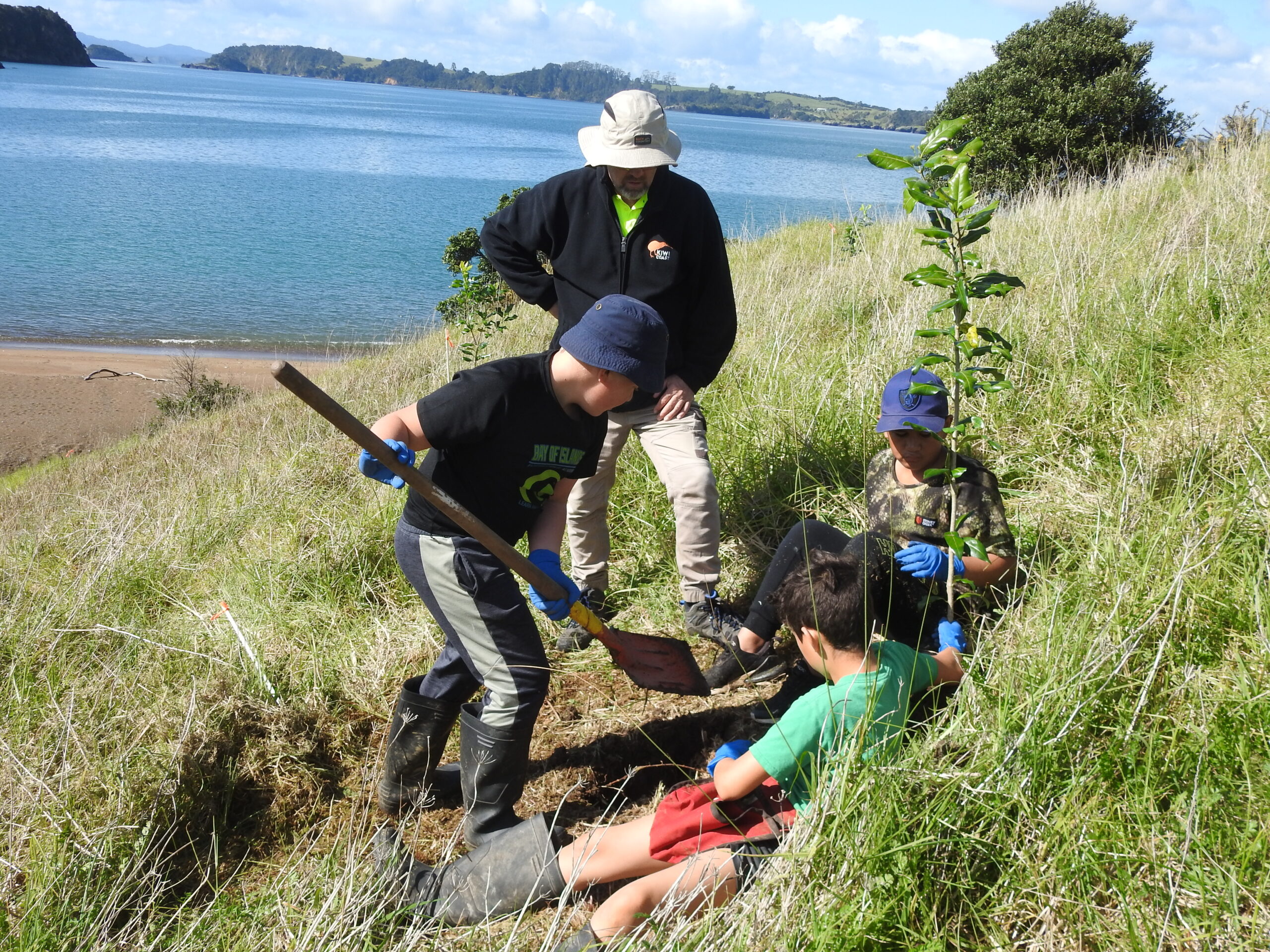 Andrew Mentor, Kiwi Coast, helps Te Tii students plant on the Purerua Peninsula 
